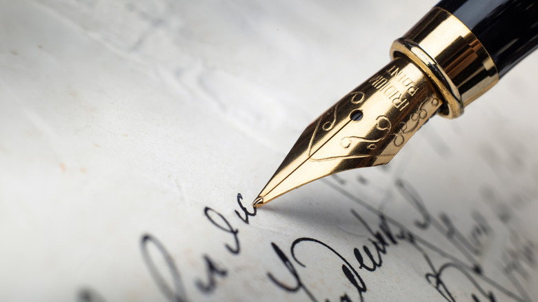 Un gros plan d'un stylo plume écrivant des lettres sur un morceau de papier