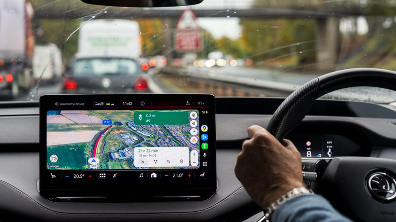 Personne conduisant dans une circulation dense avec Google Maps affiché sur le système d'infodivertissement central