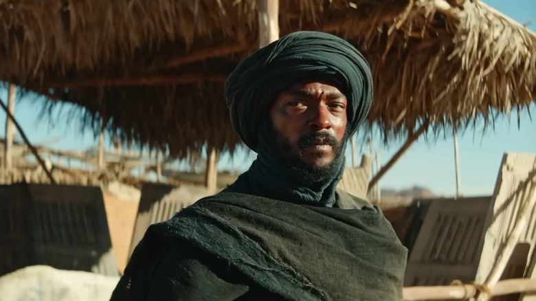 Anthony Mackie dans le rôle du bandit debout devant une cabane en herbe dans Desert Warrior