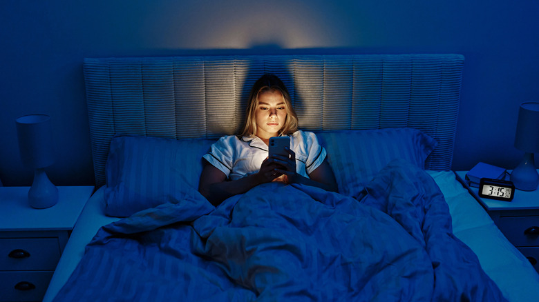 Femme éveillée au milieu de la nuit en utilisant son smartphone