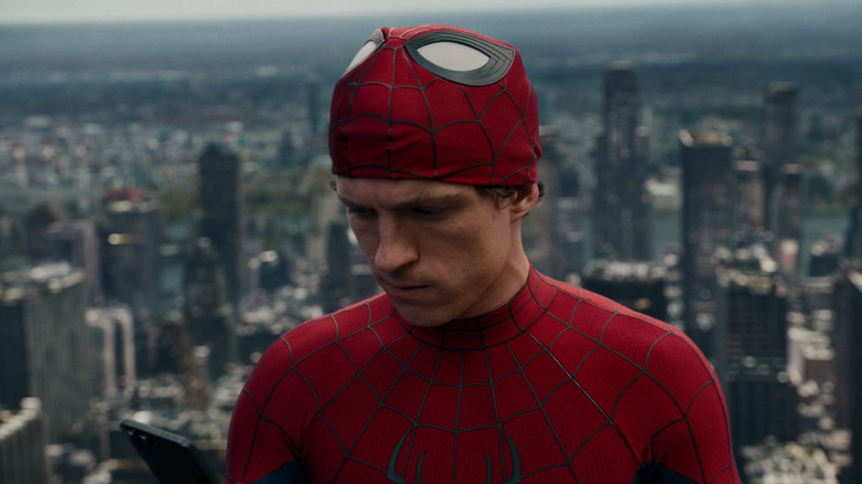 Tom Holland dans le rôle de Spider-Man avec son masque regardant son téléphone dans Spider-Man : No Way Home