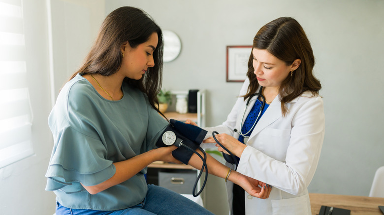 Femme faisant vérifier sa tension artérielle par un médecin