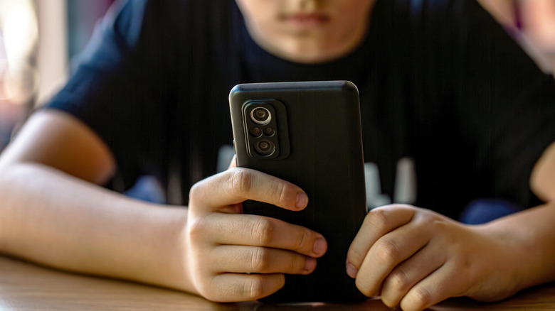 Un enfant tenant un smartphone.