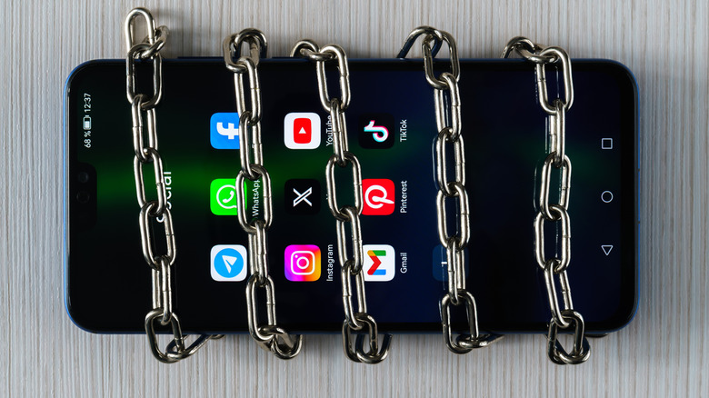Smartphone avec applications sur l'écran et chaîne enroulée autour
