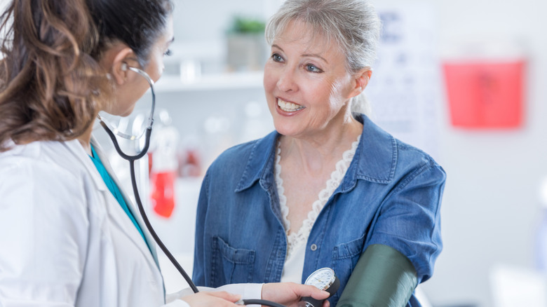 Médecin parlant avec un patient tout en prenant sa tension artérielle