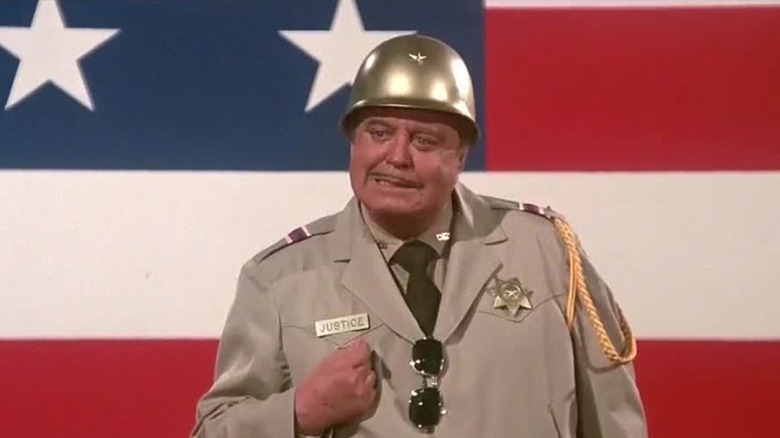 Jackie Gleason dans le rôle du shérif Buford T. Justice devant un drapeau dans Smokey and the Bandit Part 3
