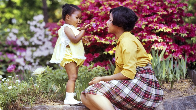 Un bébé montrant une fleur à sa mère dans les années 1970