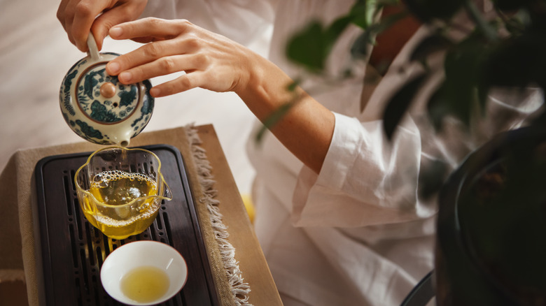 Personne versant une tasse de thé vert