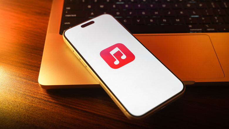 Écran de démarrage de musique Apple sur un téléphone conservé sur un ordinateur portable