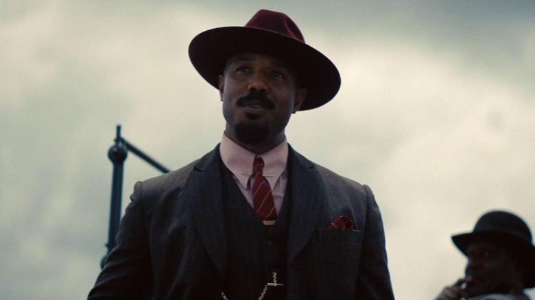 Michael B. Jordan dans le rôle de Smoke debout près de la voiture dans Sinners