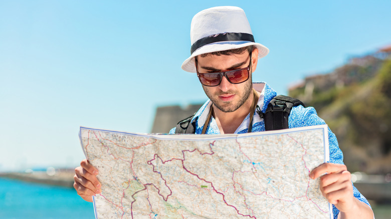 Un touriste souriant avec carte et sac.