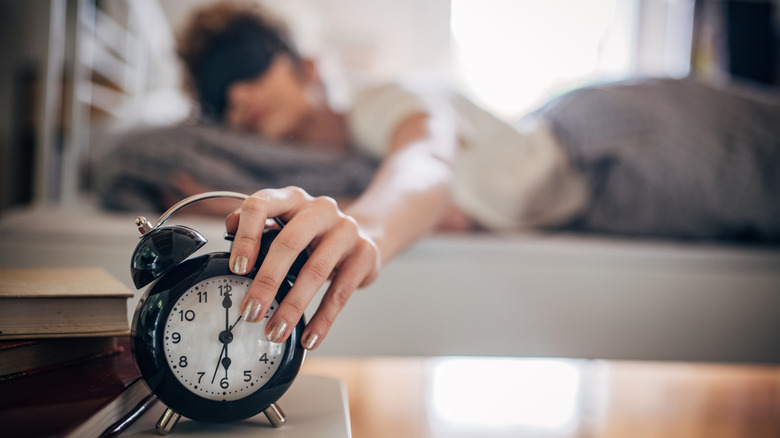Femme se réveillant et éteignant un réveil