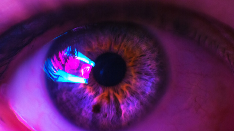 Oeil humain féminin avec des couleurs néon qui s'y reflètent