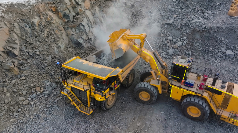 Machinerie lourde déversant de la roche dans un camion-benne dans une mine à ciel ouvert