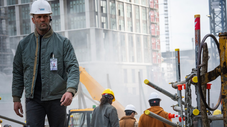 Jason Statham dans le rôle de Levon Cade portant un casque et traversant une zone de construction dans A Working Man