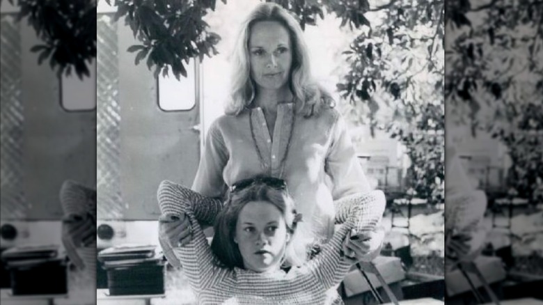 Une photo en noir et blanc montre une jeune Melanie Griffith assise sur une chaise tandis que sa mère Tippi Hedren la serre dans ses bras par derrière.