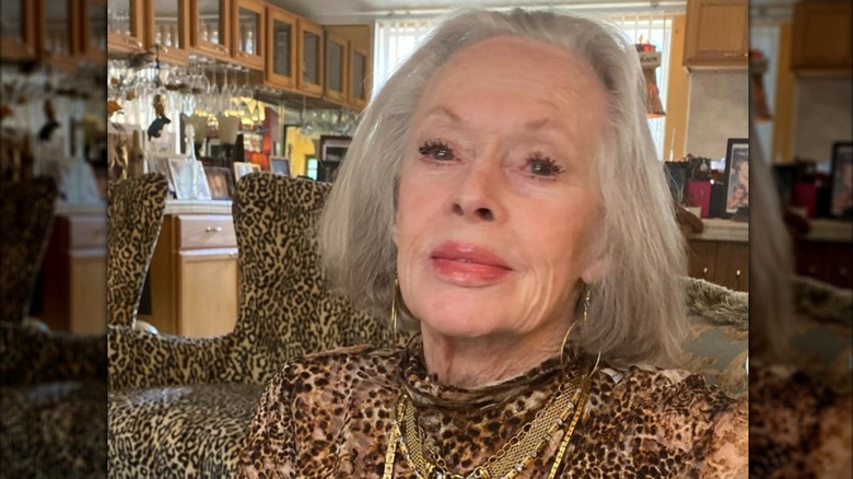 Tippi Hedren est photographiée dans une robe à imprimé animal alors qu'elle est assise dans une pièce avec des chaises à imprimé animal en arrière-plan