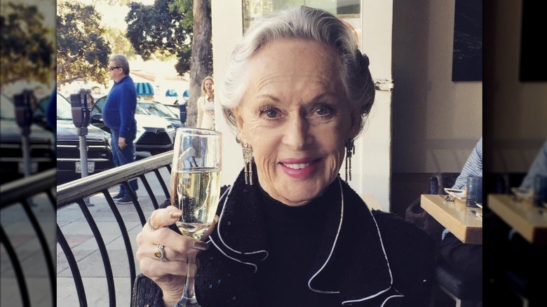 Tippi Hedren porte une veste noire et tient une coupe de champagne tout en dînant dans un restaurant