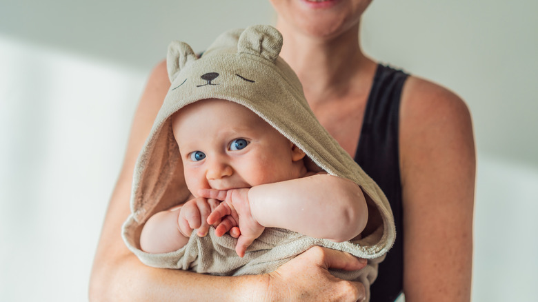 Une mère tenant son bébé dans une couverture de bain à capuche