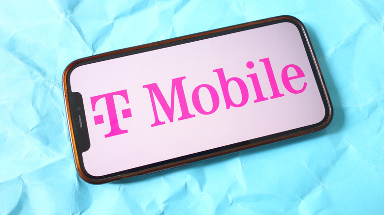 Photo d'un smartphone avec le logo rose T-Mobile, sur fond bleu