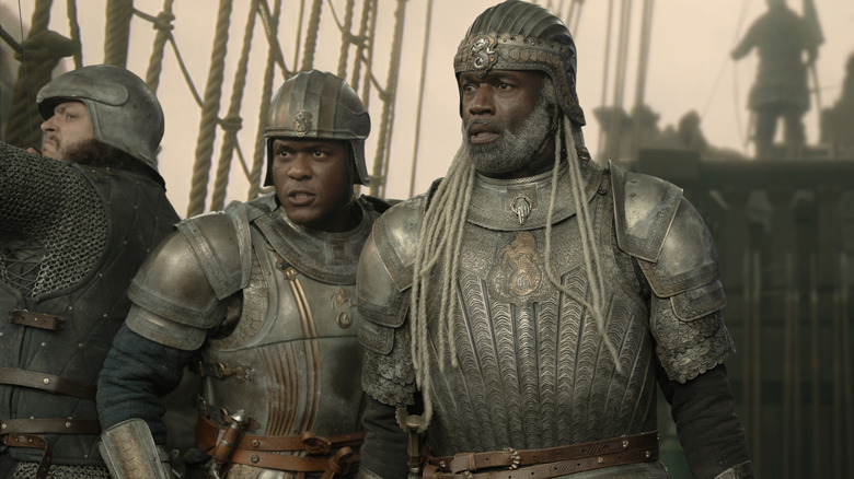 Abubakar Salim dans le rôle d'Alyn de Hull debout sur le pont d'un navire à côté de Steve Toussaint dans le rôle de Corlys Velaryon en armure complète dans House of the Dragon