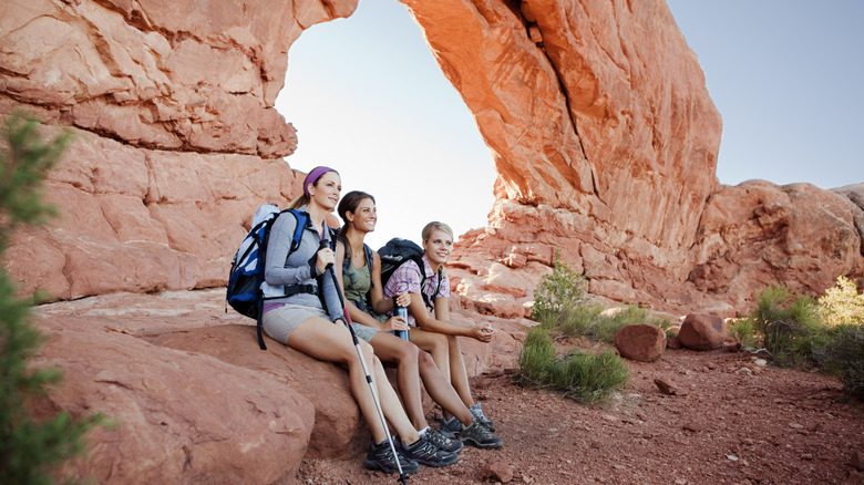 trois femmes s'assoient lors d'une randonnée dans le parc national des Arches, Utah