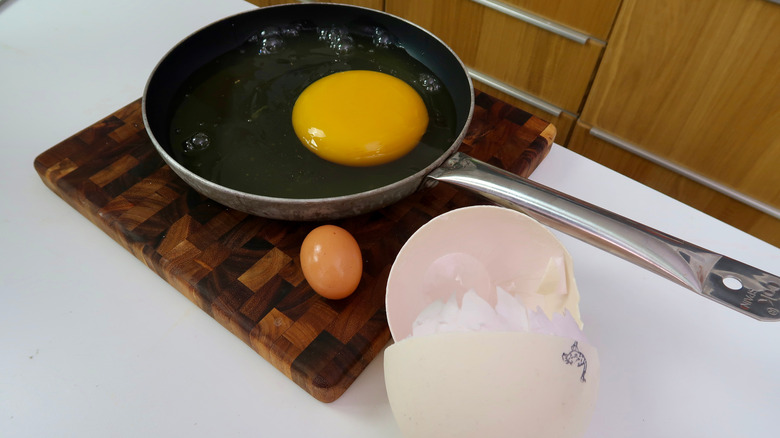 Oeuf d'autruche cassé dans une poêle