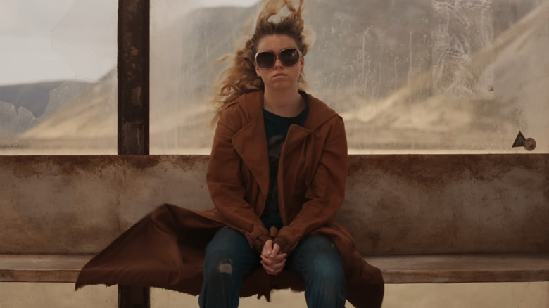 Milly Alcock dans le rôle de Kara Zor-El assise à l'arrêt de bus dans Supergirl