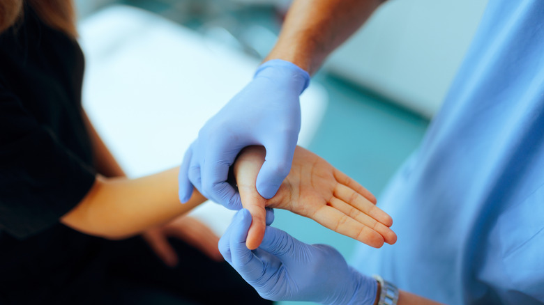 Professionnel de la santé examinant la main d'un patient pour détecter une éventuelle blessure