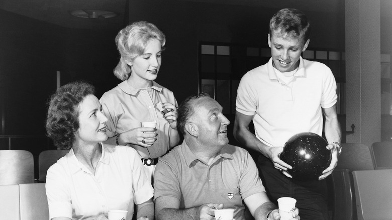 Adolescents jouant au bowling avec leurs parents dans les années 1950