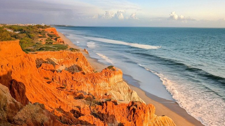 Falaises orange et vagues ondulantes sur la Praia da Falésia