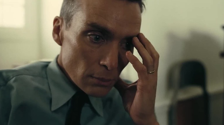 Cillian Murphy dans le rôle de J. Robert Oppenheimer tenant son visage dans Oppenheimer
