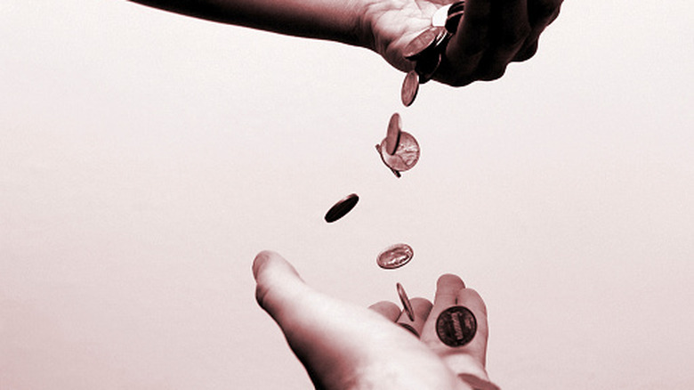 Une main laisse tomber les pièces de monnaie, une autre main les attrape.