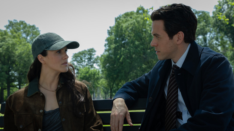 Jessica Brown Findlay dans le rôle de Charlotte Keene assise sur un banc de parc et portant un chapeau à côté d'Ashley Zukerman dans le rôle de Daniel Keene dans Silo