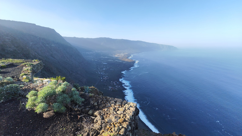 Une plage de sable volcanique noir bordée de montagnes à El Hierro.