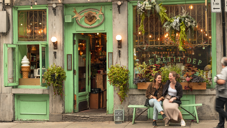 Deux femmes rient sur un banc devant un café-bistro-restaurant traditionnel de la vieille ville de Montréal