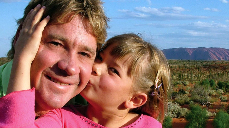 La jeune Bindi Irwin en haut rose embrasse son père, Steve Irwin, sur la joue.
