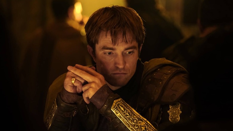 Robert Pattinson dans le rôle d'Antinous assis à une table dans L'Odyssée