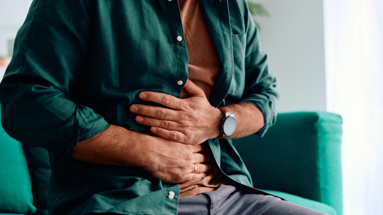 Homme tenant les deux mains sur le ventre dans la douleur