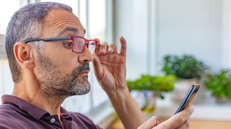 Homme rencontrant des problèmes de vision en regardant son téléphone