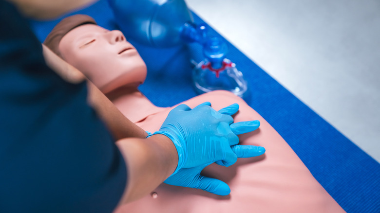 Quelqu'un avec des gants effectuant la RCR sur un mannequin de test.