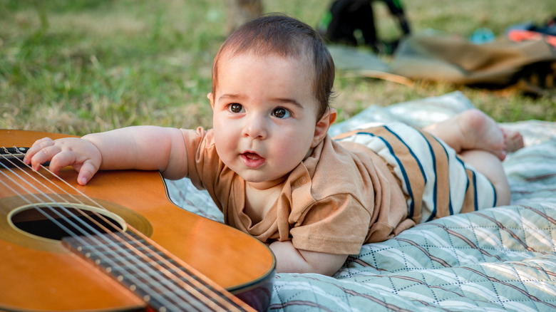 Un bébé qui rampe vers une guitare