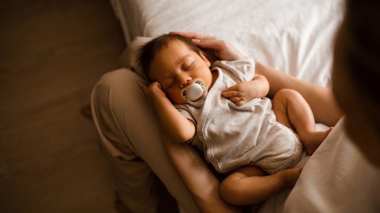 Un bébé allongé sur les genoux de sa maman