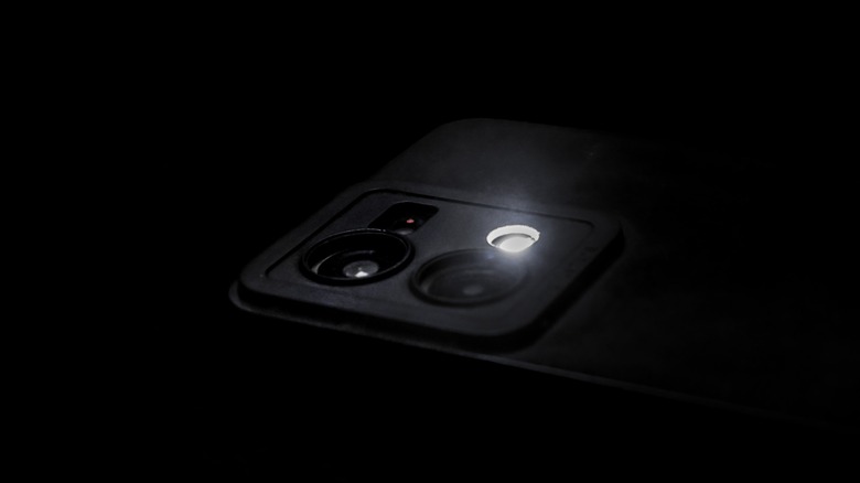L'appareil photo d'un smartphone se cogne dans l'obscurité avec le flash activé.