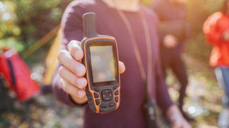 Une personne tient un téléphone satellite devant la caméra au soleil