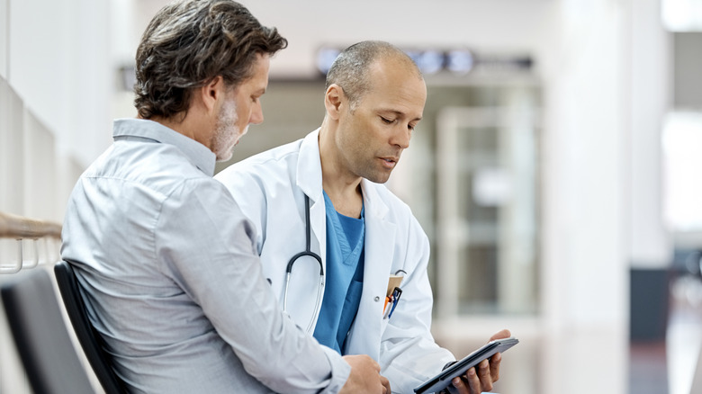 Médecin parlant avec un patient masculin tout en lisant une tablette