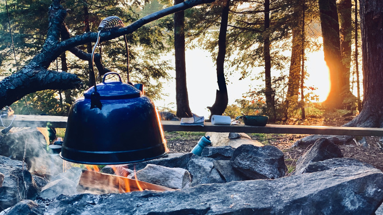 faire chauffer une bouilloire sur un feu de camp pendant le camping dans l'arrière-pays