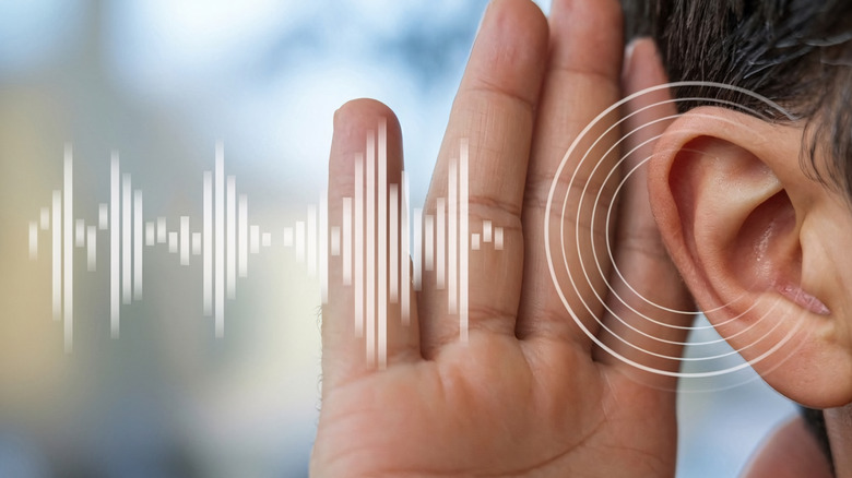 Homme tenant une main à son oreille avec des ondes sonores ajoutées à côté