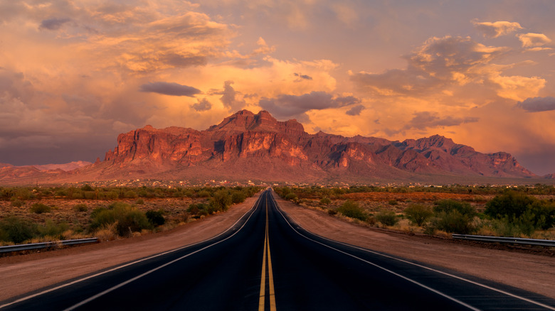 Longue route droite vers les Superstition Mountains en Arizona au coucher du soleil