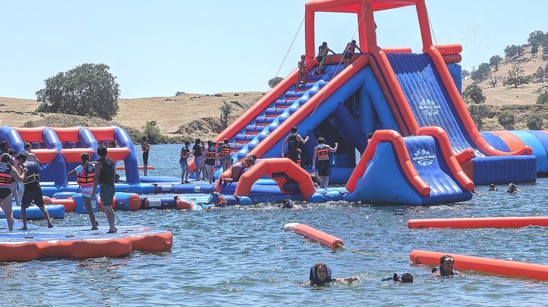 vue rapprochée des invités jouant sur des toboggans gonflables rouges et bleus et un parcours d'obstacles au parc aquatique Splash-n-Dash